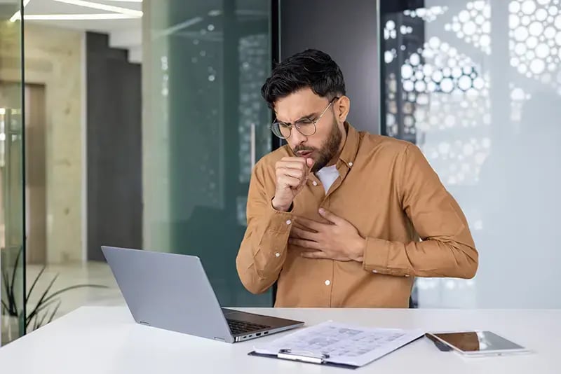 Sick man coughing in an office